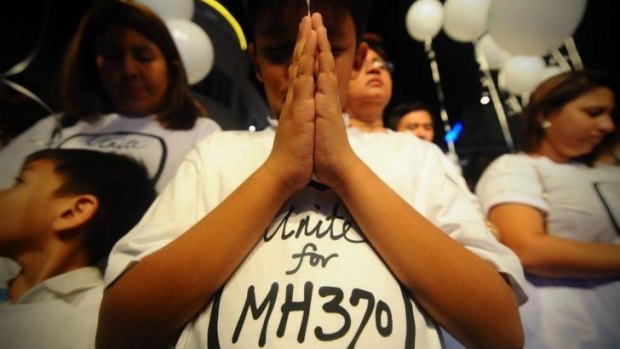 Hope: A young Malaysian boy prays at an event for the missing Malaysia Airline plane Kuala Lumpur.