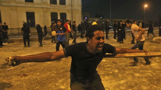 Opponents of ousted President Mohammed Morsi prepare to throw rocks towards pro-Mursi supporters during clashes in downtown Cairo, Egypt.