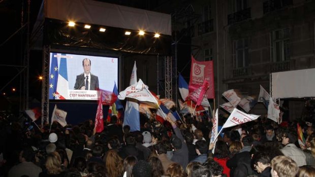 First round ... Supporters of Francois Hollande, Socialist Party candidate for the 2012 French presidential election, react as they watch a giant screen outside the Rue de Solferino Socialist Party headquarters in Paris as Hollande delivers his speech.