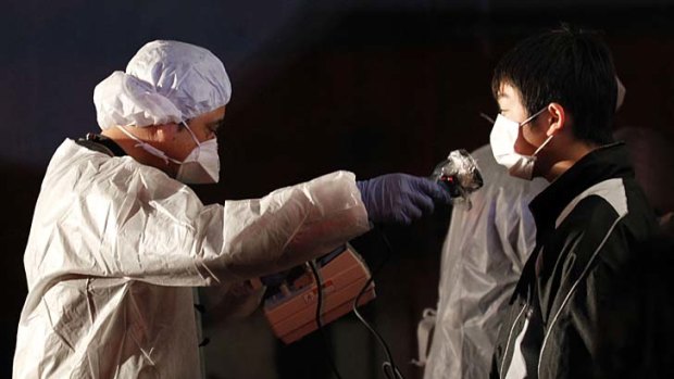 Official in protective gear scans for signs of radiation on a man who is from the evacuation area  near the Fukushima Daini nuclear plant in Koriyama.