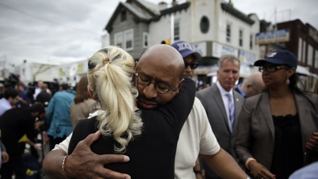 Philadelphia Mayor Michael Nutter, centre right, hugs Lori Dee Patterson, a nearby resident, after she handed him a cup of coffee after he spoke at a news conference.