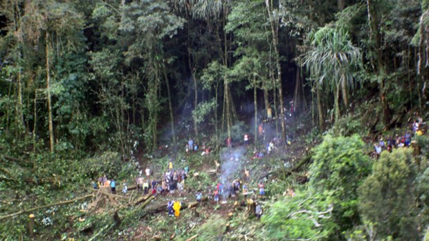 Rescue workers and nearby villagers clear the crash site.