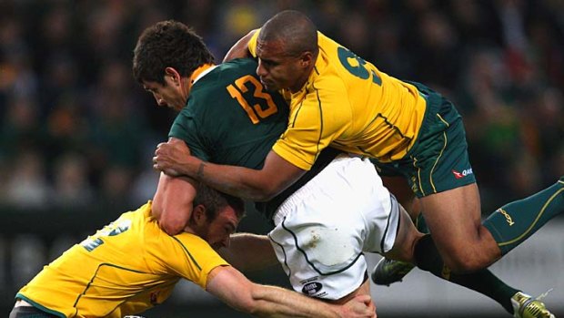Jaque Fourie is tackled by Pat McCabe (L) and Will Genia (R) as the Wallabies shut down the Springboks.