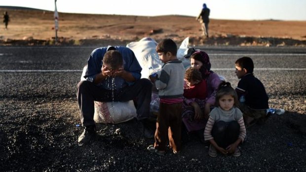 Homeless: Kurdish refugees sit on the side of the road after fleeing Kobane.