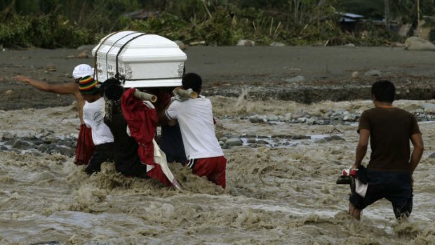 More to come ... Filipinos cross a river to bury a relative, who died in a flash flood caused by a hurricane.
