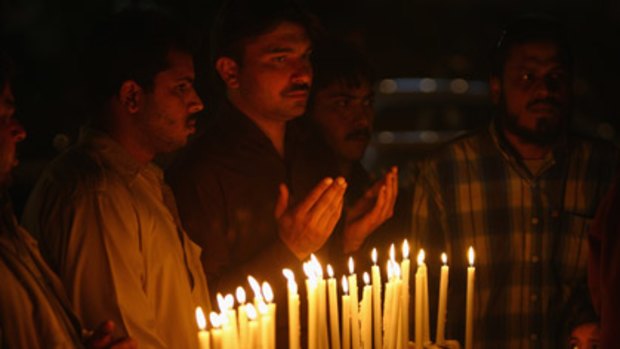 Respect ... people light candles and pray in a memorial service at the scene of the killings in Lahore.