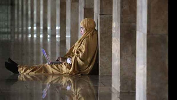 An Indonesian Muslim woman checks her laptop after an afternoon prayer at a mosque in Jakarta, Indonesia. <i>Picture: AP Photo/Irwin Fedriansyah</i>
