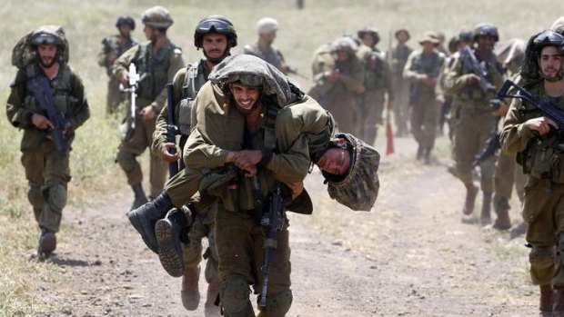 Right to strike: An Israeli soldier carries another soldier during training close to the ceasefire line between Israel and Syria on the Israeli occupied Golan Heights on Tuesday.