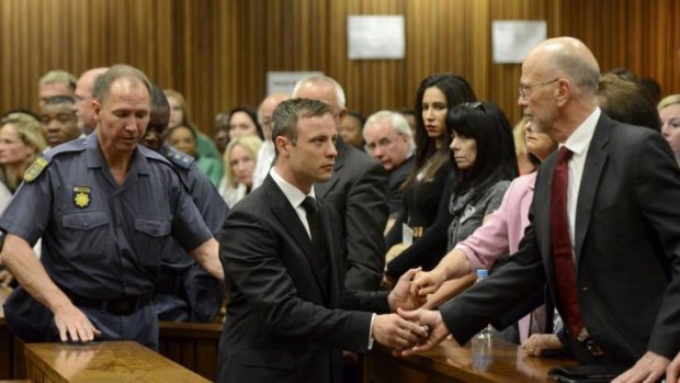 Paralympian Oscar Pistorius holds the hands of his uncle Arnold as he is taken down to the holding cells.