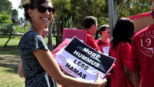 A protester holds a 'more hummus, less Hamas' sign.
