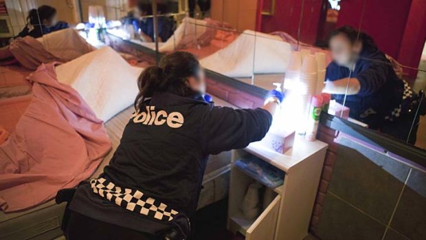 A police officer searches a room at a Melbourne brothel.