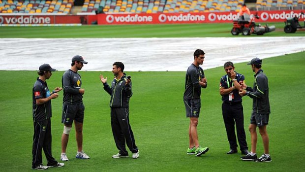 Soggy wait: Members of the Australian side inspect the ground on the rain-affected day two of the Test.