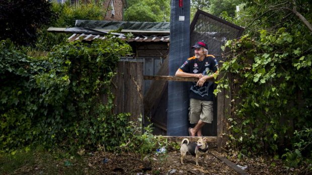 STILL WAITING: David Creech and Mahal the pug at the hole in the back fence of the Lowrie Street, Dickson, home.