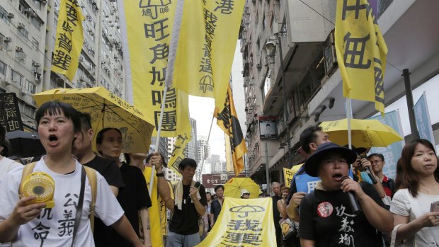 Protesters carry a banner with Chinese words "I want genuine universal suffrage" as they march on a downtown street.