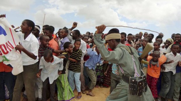 An al-Shabab member controls civilians during a Somali demonstration.