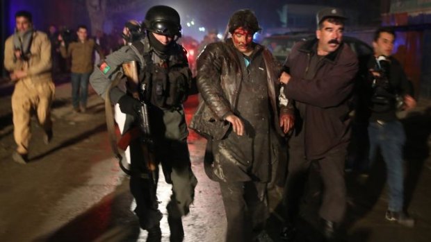 Suicide attack: Afghan police forces help an injured man at the site of the explosion.