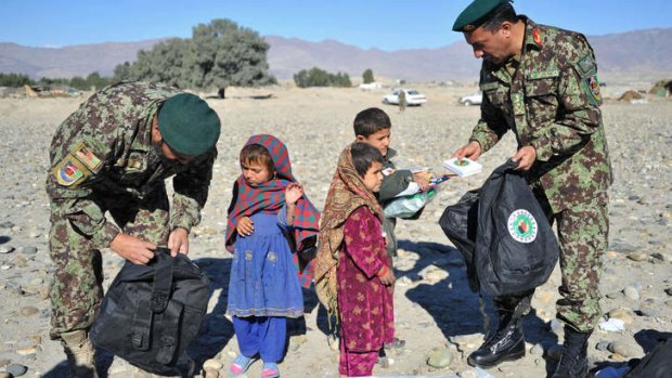 Afghan National Army soldier donate bags and stationery to schoolchildren.