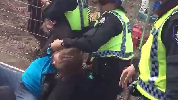 A protesters is hand-cuffed by police after the fences guarding the site were pushed down.