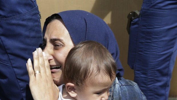 A refugee holding her child is detained in Bicske, Hungary on Thursday.