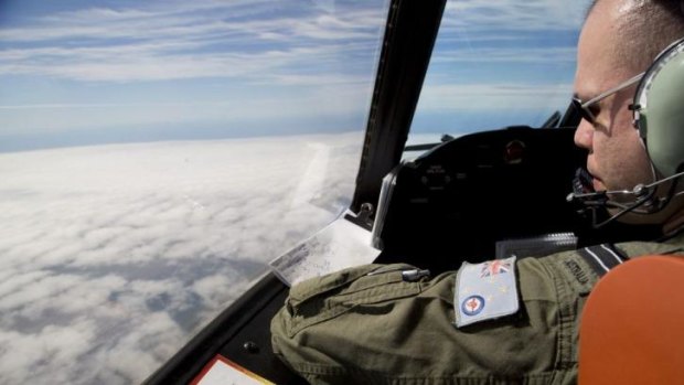 Flight Lieutenant Jayson Nichols looks out the cockpit of a Royal Australian Air Force AP-3C Orion aircraft over clouds while searching for missing Malaysian Airlines flight MH370.