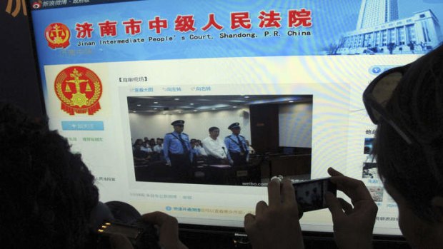 A journalist takes photos of a microblog by Jinan Intermediate People's Court showing disgraced former Chinese politician Bo Xilai during his trial.