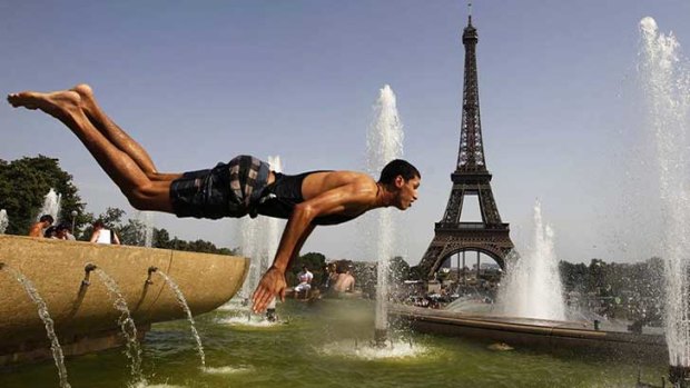A man jumps into a fountain near the Eiffel Tower on a hot day in Paris, France.