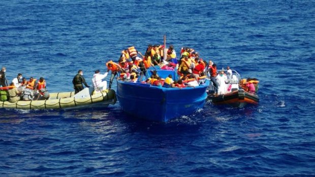 Italian Navy (left) help refugees to climb on their boat in the Mediterranean Sea on September 8. Thousands of migrants have been rescued by authorities in recent weeks.