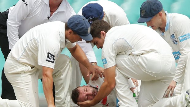 NSW players assist Hughes on the field.