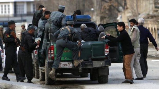 US charity targeted ... Afghan policemen evacuate foreigners from the site of the Taliban attack in Kabul. 