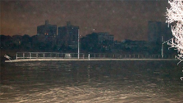 A large piece of the Riverwalk floats down the Brisbane River about 1am on January 13.