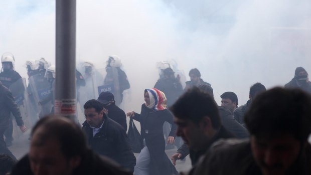 People run as riot police use tear gas and water cannons on the crowd.