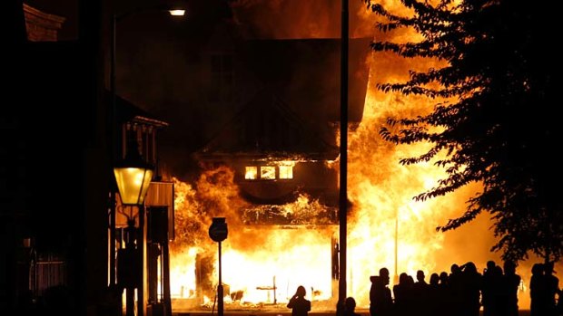 Up in flames ... a shop is set on fire as rioters gather in Croydon, south London.