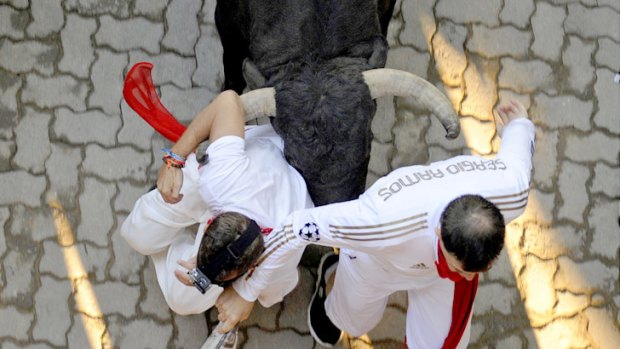 A runner is knocked down by Victoriano del Rio fighting bulls at the entrance to the bullring.