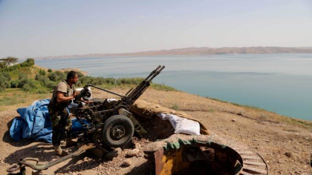 A Kurdish Peshmerga fighter prepares his weapon at his combat position near the Mosul Dam.