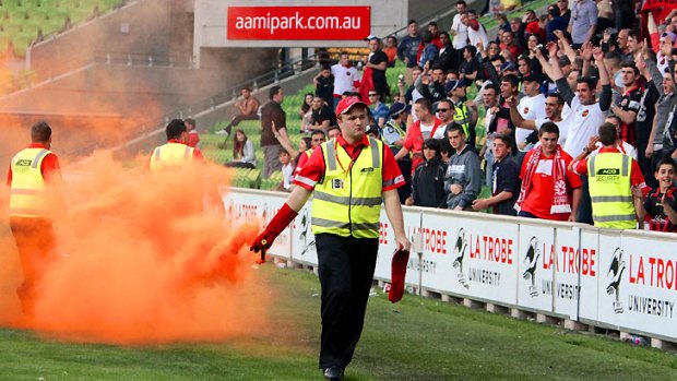 Terrible consequences...A match official carries away a flare thrown from the crowd at AAMI Park.