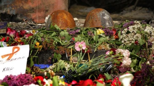Charred remains: Two burnt police helmets among flowers left at the entrance of the police station in Mariupol.