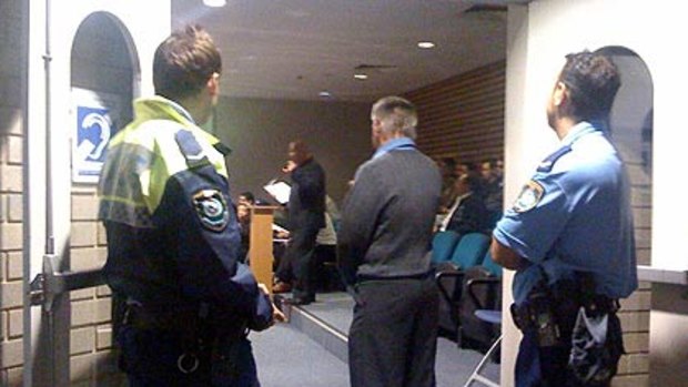 Captive audience ... police wait at the door of Fairfield Council before they removed two residents who the mayor said were disruptive.