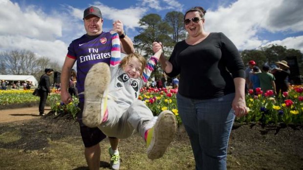 Swinging through the tulips are father Matt, daughter Matilda, 4, and mother Erin Askew at Floriade.
