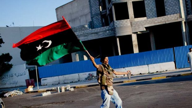 He's gone... a rebel shouts anti-Muammar Gaddafi slogans in the streets of Libya's capital, Tripoli, as he celebrates the dictator's downfall.