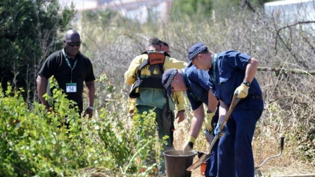 British police officers dig for evidence during the search of an area of scrubland in Portugal.