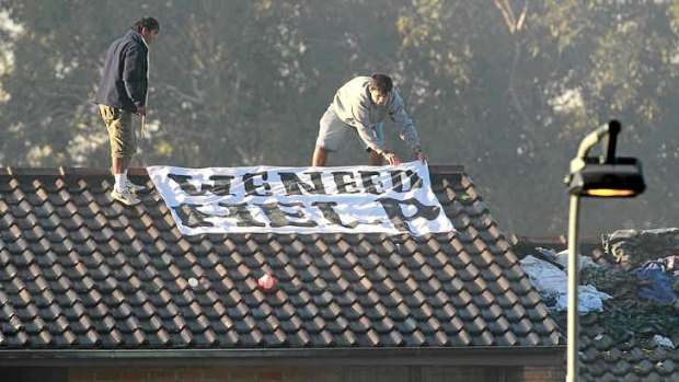 At risk: Protesters lay out a sign on a roof at Villawood detention centre.