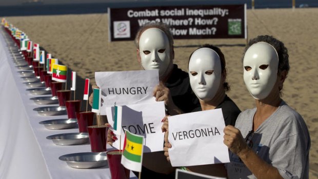 Masked ball ... protesters at a table set with empty plates and national flags at Copacabana beach during the United Nations Conference on Sustainable Development in Rio de Janeiro, Brazil.