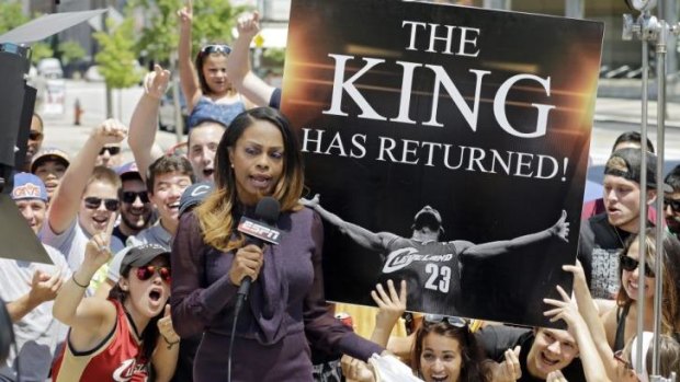 Homecoming king: Fans whoop it up behind an ESPN reporter outside Quicken Loans Arena in Cleveland, after NBA basketball star LeBron James announced he would return to the Cleveland Cavaliers.