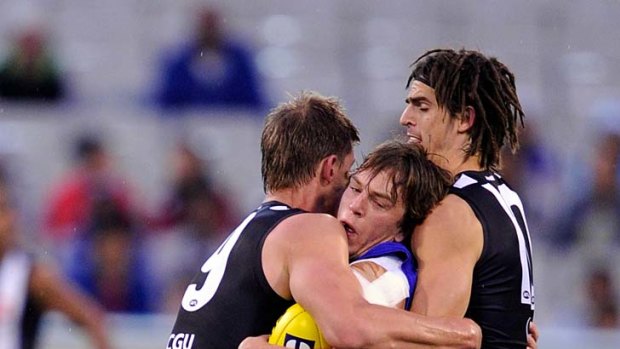 Squeezeplay: Pies Cameron Wood and Scott Pendlebury trap Bulldog Liam Picken.