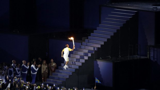 Brazilian marathoner Vanderlei de Lima runs up the steps with the Olympic flame.