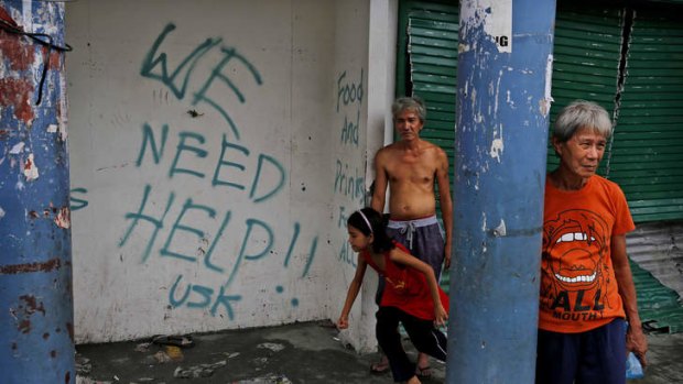 Desperate plea: Residents stand next to a sign requesting aid in Tacloban.