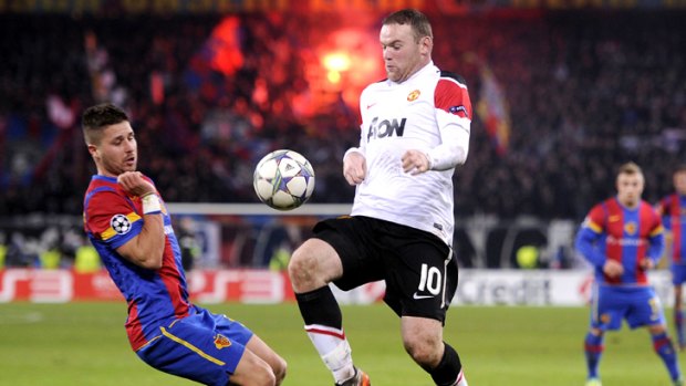 Manchester United forward Wayne Rooney vies for the ball with FC Basel's David Angel Abraham.