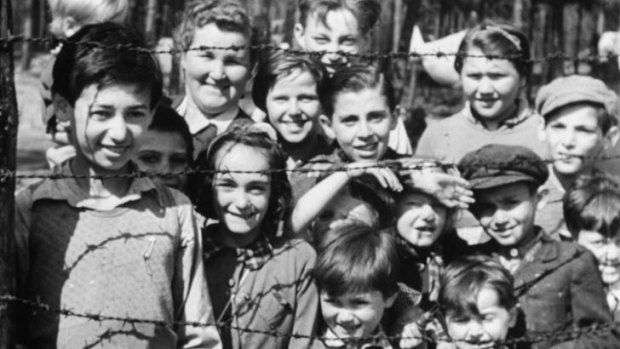 Innocence: A still of children smiling through through barbed wire, shot on April 18-20, 1945.