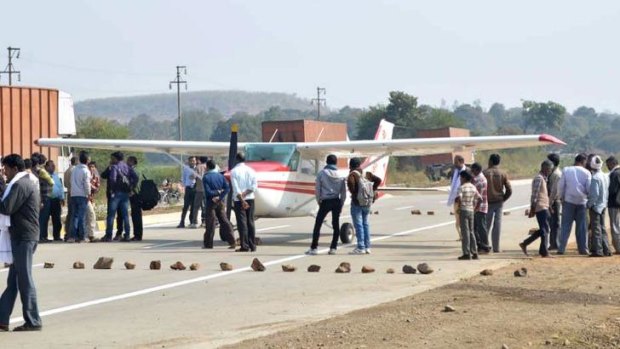 Indian officials and bystanders gather around a light aircraft after it landed on a public highway in the state of Madhya Pradesh.