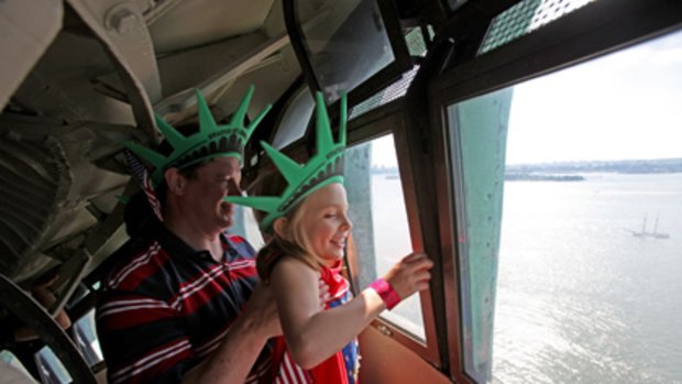 Chris Bartnick, 46, hoists his daughter Aleyna, 8, both of Merrick, New York, for a better view from the crown of the Statue of Liberty.